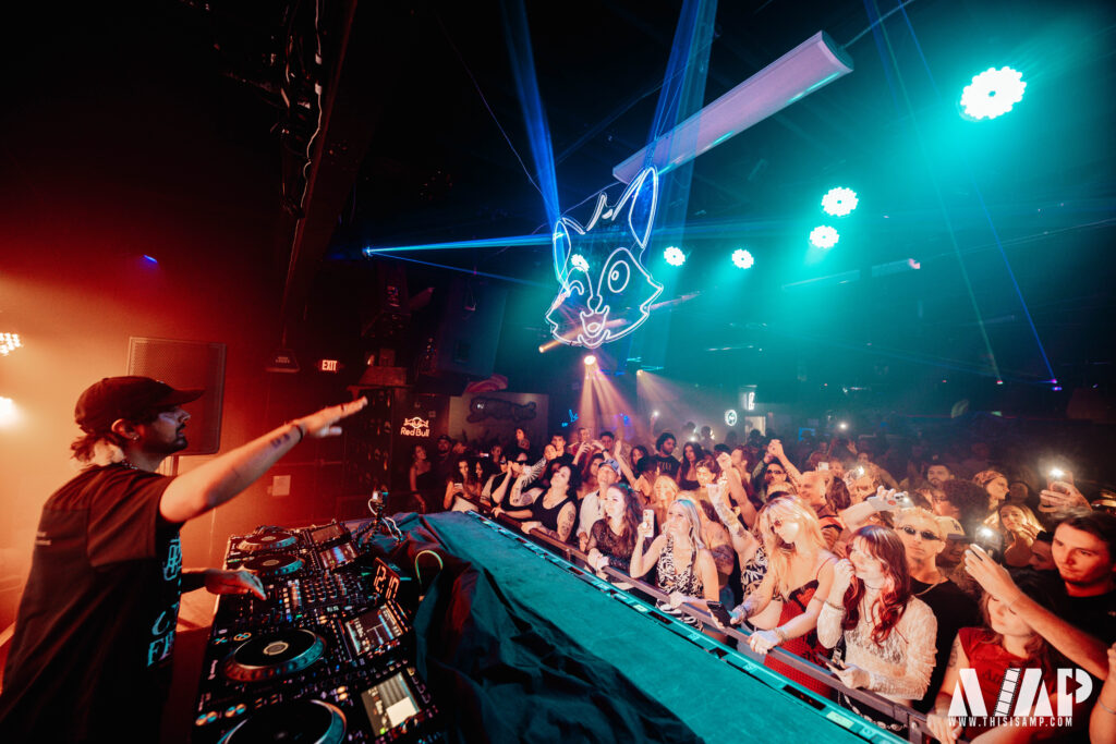 Jai Wolf performing under teal stage lights, photographed by AMP Studios